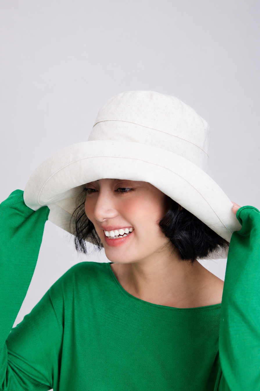Melba Lane – Tossa hemp beige wide-brim bucket sun hat held at the brim, front view, handmade linen-cotton UPF 50+ hat