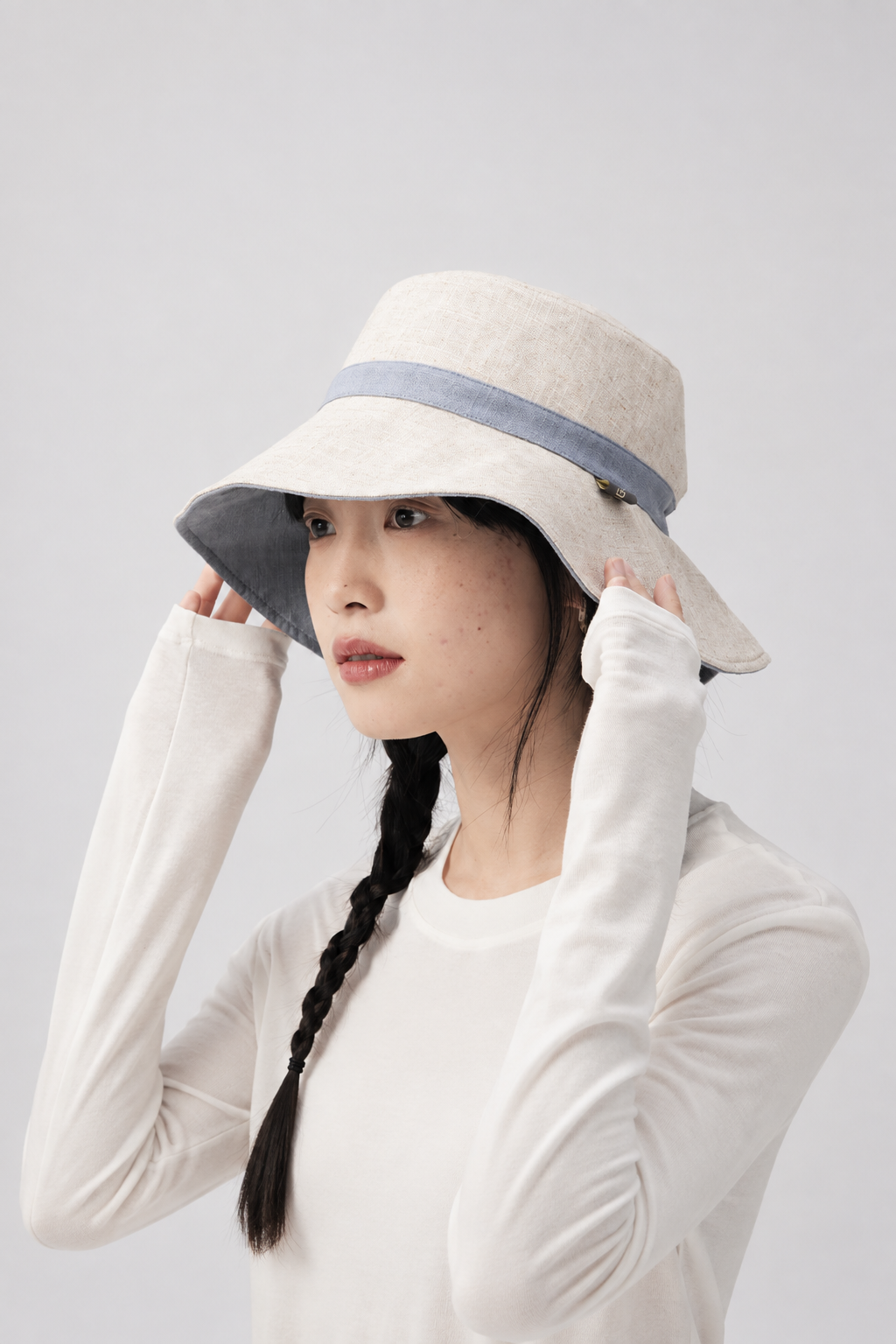 Melba Lane – Tinos reversible sun hat turned to its natural linen side with a blue band, side view on model