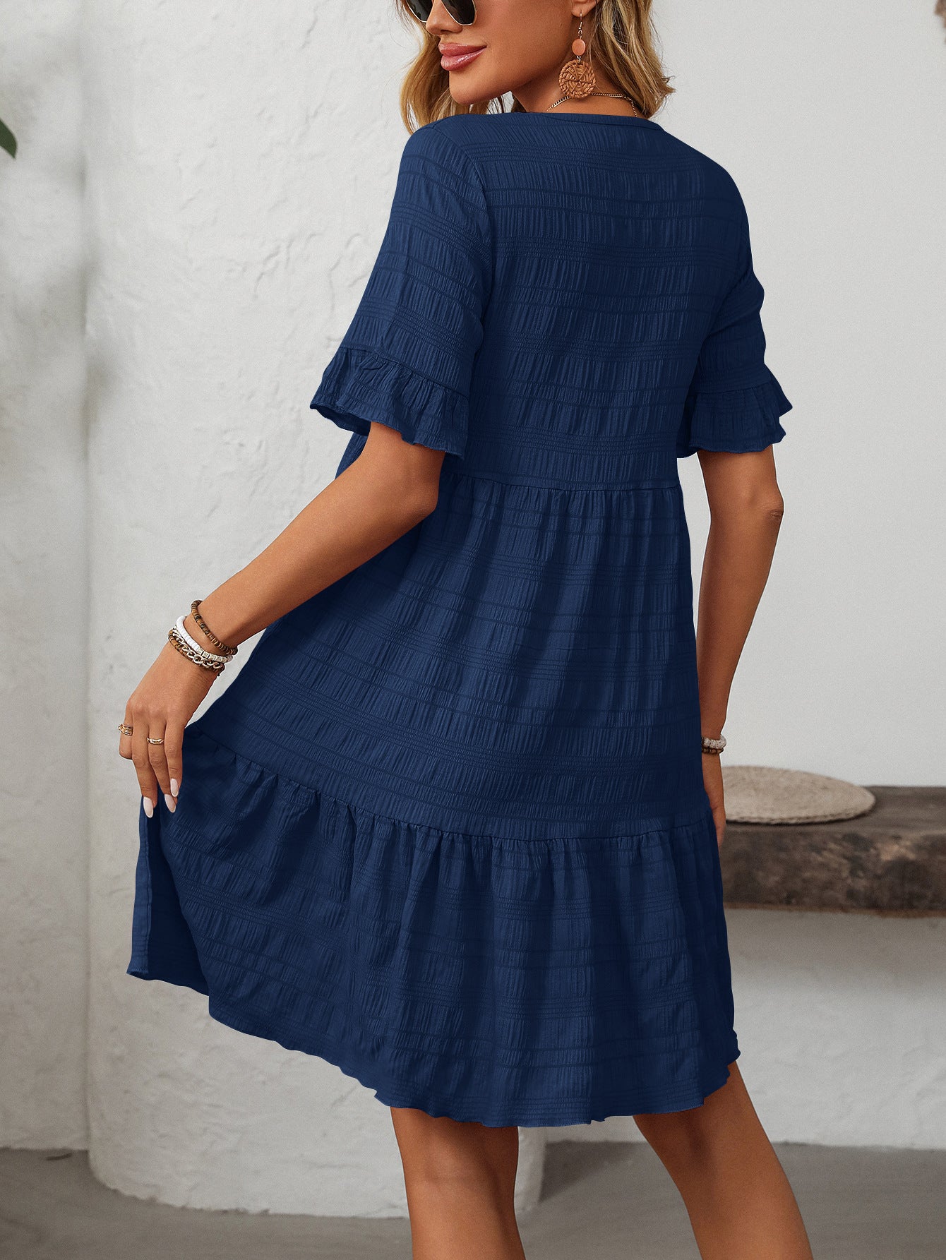 Melba Lane – Studland navy blue textured tiered short-sleeve dress, front view of the tiered hem with hands at the sides, AU women's sizes