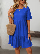 Melba Lane – Studland royal blue textured tiered short-sleeve dress, front view with a hand on the straw tote strap, AU women's sizes
