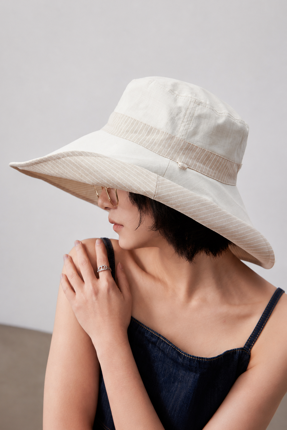 Melba Lane – Kythira beige reversible wide-brim sun hat worn plain side out, three-quarter view with the striped underbrim showing