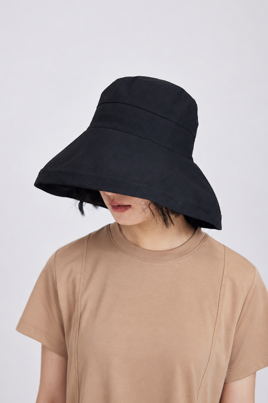 Melba Lane – Tossa black wide-brim sun hat worn with the brim tilted low over the eyes, front view