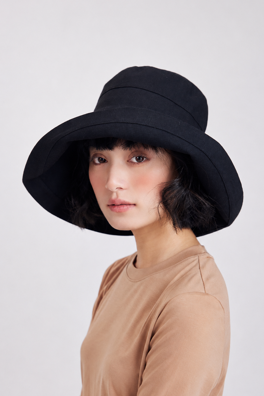 Melba Lane – Tossa black wide-brim bucket sun hat, three-quarter front view on model in a tan tee