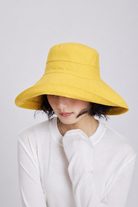 Melba Lane – Tossa yellow wide-brim foldable sun hat seen from a three-quarter angle, showing the seamed crown and self-fabric band