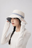 Melba Lane – Tinos reversible sun hat turned to its natural linen side with a blue band, side view on model